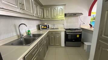 A compact kitchen with stainless steel appliances, a microwave, and a stove.