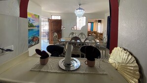 Uma sala de jantar com mesa, cadeiras, um candelabro e um objeto decorativo na parede.
