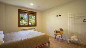 A bedroom with a bed, a chair, a radiator, a window, and a drying rack.