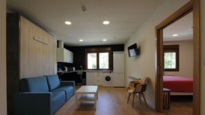A compact living space with a kitchenette, a sofa, a table, and a bed. - Accessible Rural Apartments La Rioja (Torrecilla en Cameros)