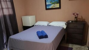 Une chambre à coucher avec un lit, des oreillers, une table de chevet avec une lampe et un tableau au mur.