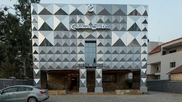 A modern building with a geometric facade, labeled 'Cuba Suites' and 'ALGON HOUSE.' - Room-cubana Suites - Guest Room (Abuja)