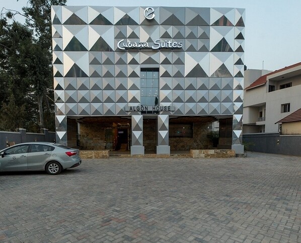 Un edificio moderno con fachada geométrica, que muestra las etiquetas 'Cuba Suites' y 'ALGON HOUSE'.