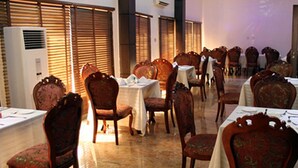 A dining area with wooden chairs and tables, air conditioning units, and a tiled floor. - Room-cubana Suites - Guest Room (Abuja)
