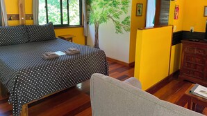 Une pièce comprenant un lit, une petite table, une chaise, un meuble en bois et une fenêtre avec des rideaux.