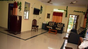 A spacious living room with a large flat-screen TV, a wooden cabinet, and two sofas.