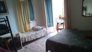 Quarto com duas camas, uma cadeira, janela com cortinas e vista para o exterior.