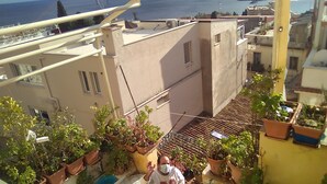 A balcony with potted plants, a small table, and a view of the sea. - Room-beautiful Double Room (Taormina)
