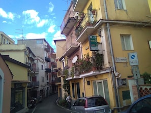 Una calle estrecha con edificios amarillos, balcones con plantas y un cartel de B&B Casa Giulio.
