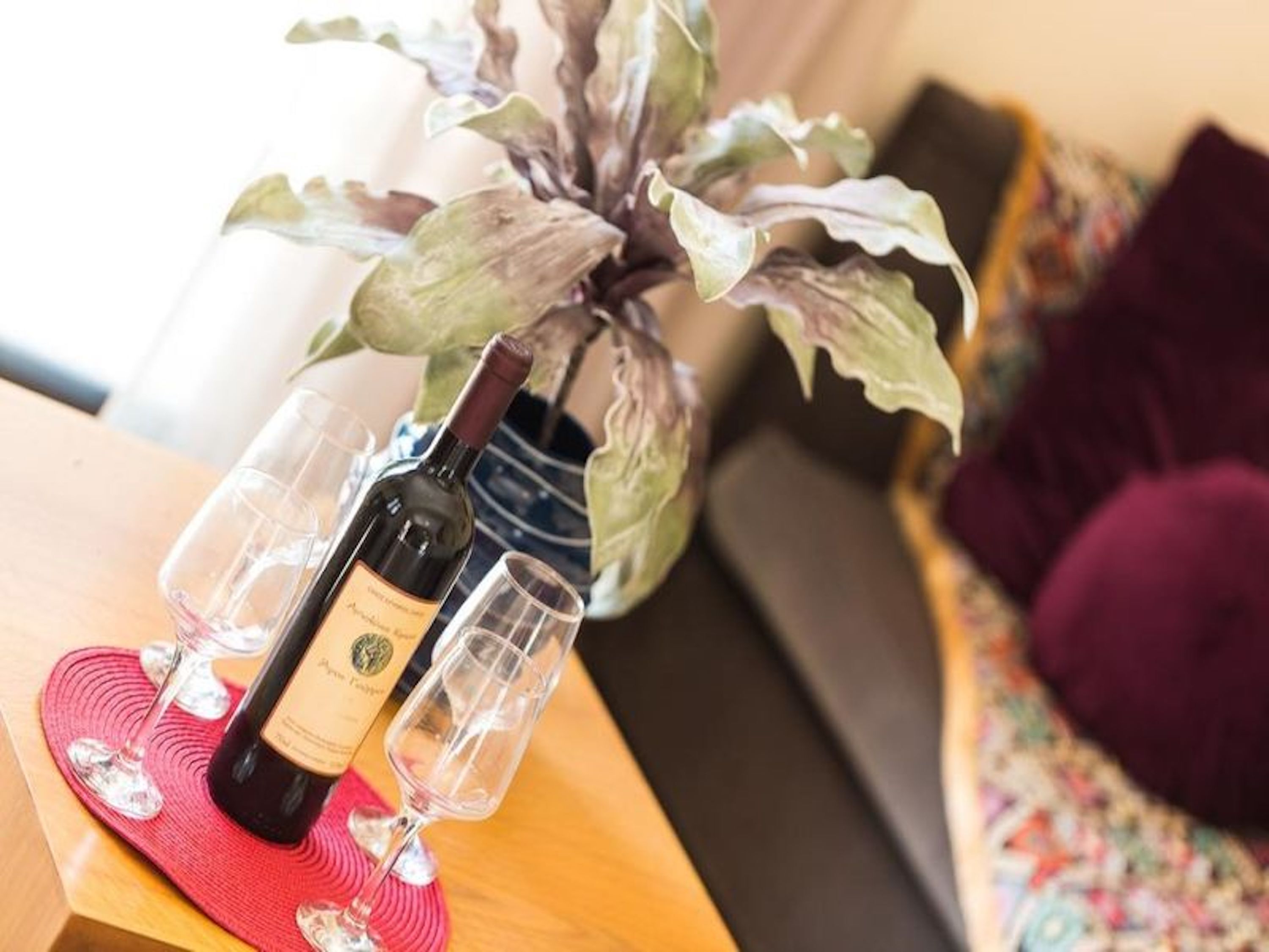 A bottle of wine on a table with a glass and a red mat.