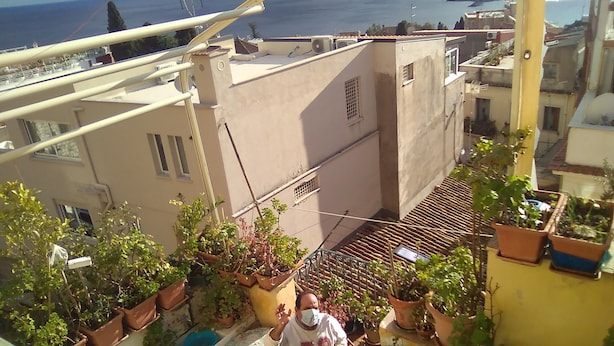 Ein Balkon mit Blumentöpfen, einem kleinen Tisch und Blick auf das Meer.