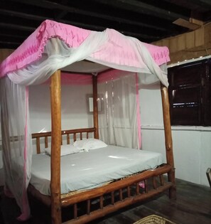 A four-poster bed with a canopy, wooden frame, and white bedding.