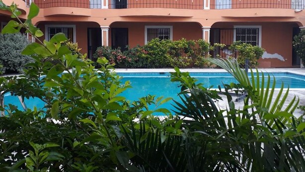 A multi-story building with a swimming pool in the foreground. - Apartahotel Next Nivel - Two Bedroom Apartment (Punta Cana)