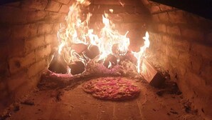 Ein Pizzaofen mit einer Pizza darin, umgeben von Flammen.