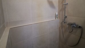 Ein Duschbereich mit Handbrause und Armatur an der Wand.