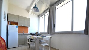 Kompakti keittiö, jossa on ruokailutila, sohva ja ikkuna, josta tulee luonnonvaloa.