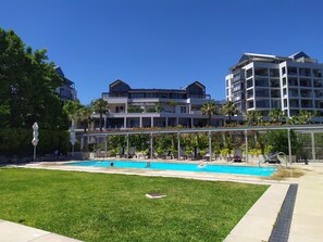A modern hotel with a swimming pool, outdoor seating, and lush landscaping. - V&a Waterfront Marina Yacht Basin - 3 Bedrooms (Cape Town)