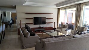Un salon moderne doté d’un téléviseur à écran plat, de canapés, d’une table basse et d’un coin repas avec des chaises et une table.