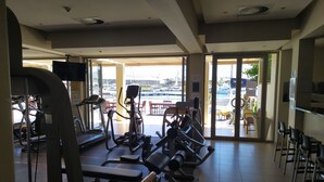 Une salle de sport équipée de tapis de course, de vélos elliptiques et de bancs d’haltères.
