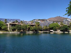 A resort with multiple-story buildings, a body of water, and a hilly landscape in the background. - V&a Waterfront Marina Yacht Basin - 3 Bedrooms (Cape Town)