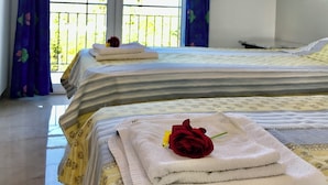 Habitación de hotel con dos camas, un balcón y aire acondicionado.