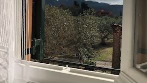 Una ventana con vistas a un paisaje montañoso y un edificio a lo lejos.