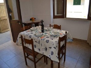 Een eettafel gedekt met borden, glazen en een fles, omringd door houten stoelen.