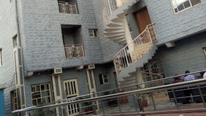 A multi-story building with a central spiral staircase, balconies, and a swimming pool. - Room-valley Front View Hotel- Guest Room (Lagos)