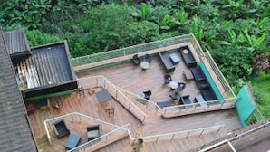 An outdoor deck with seating and a small stage, surrounded by lush greenery. - Room-valley Front View Hotel- Guest Room (Lagos)
