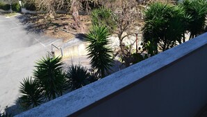 A balcony with a view of a parking lot, trees, and buildings in the background. - Holiday Home With Balcony and air Conditioning in Torre Dell'o (Melendugno)