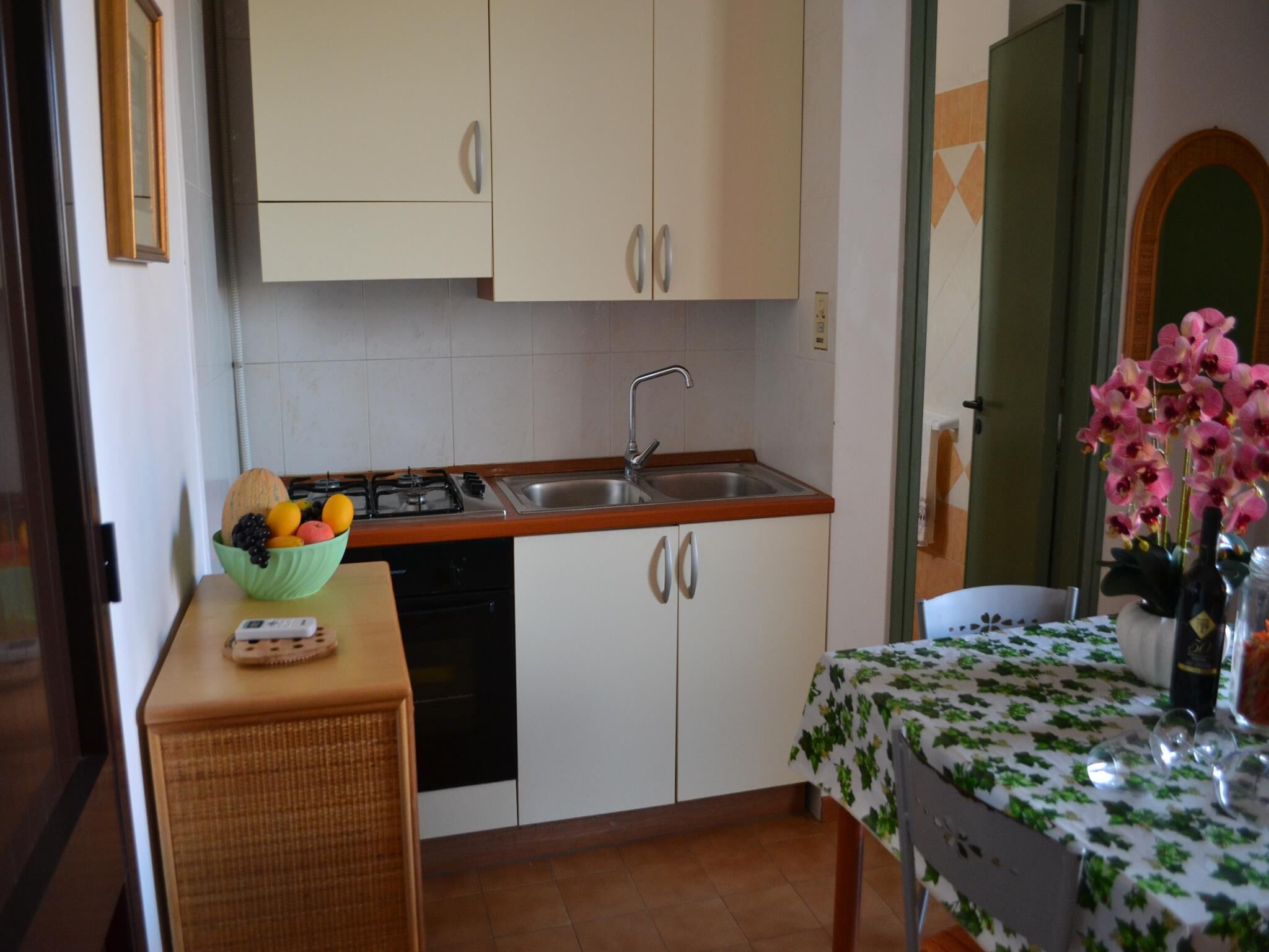 Una cocina compacta con un lavamanos, armarios y una zona de comedor con una mesa.