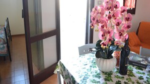 A dining area with a table set for two, a vase of pink orchids, and a bottle of wine. - Holiday Home With Balcony and air Conditioning in Torre Dell'o (Melendugno)