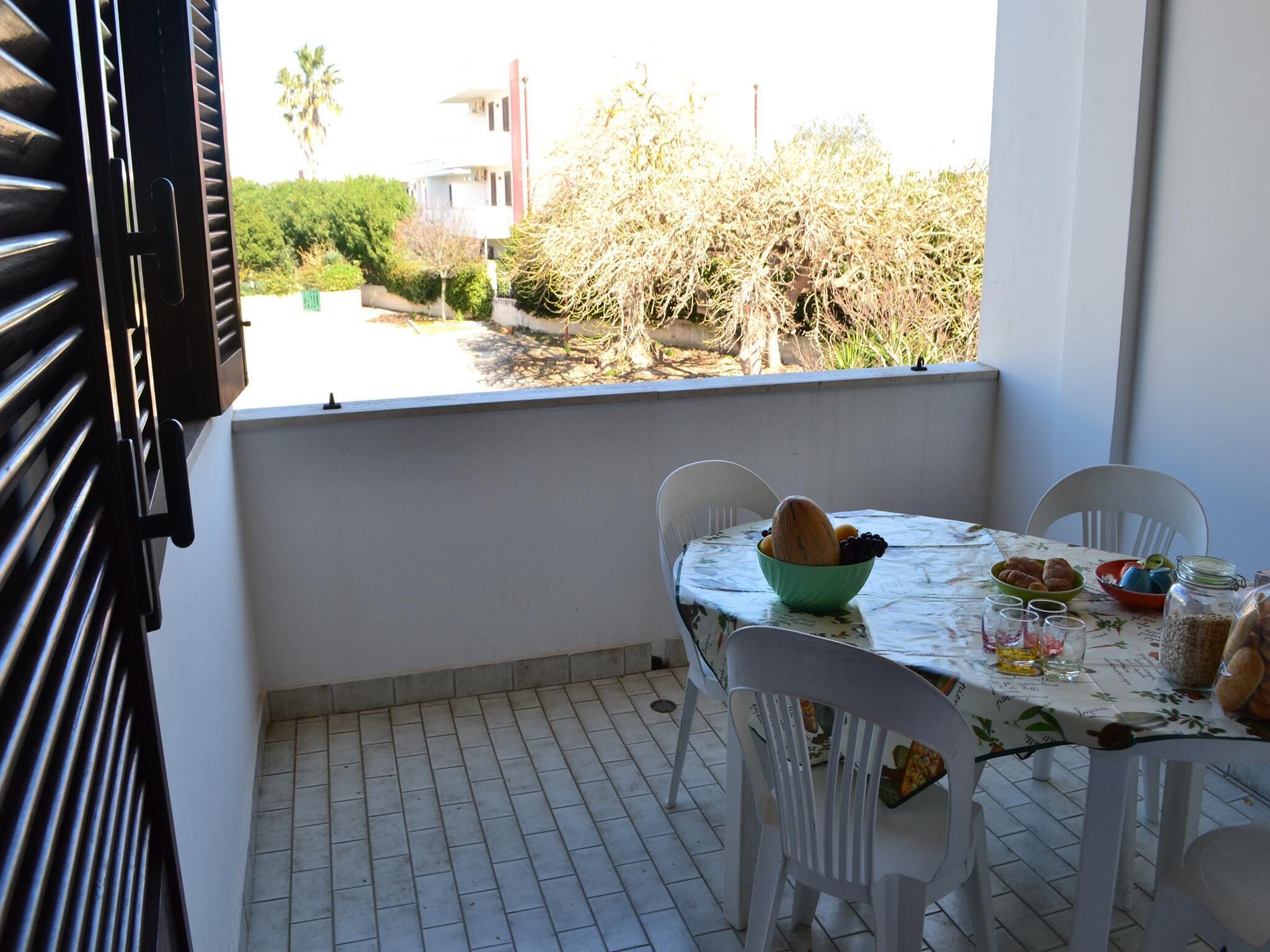 Un balcon avec une table dressée pour les repas, des chaises et une vue sur les environs.