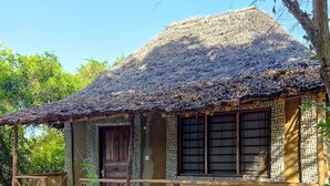 A traditional house with a thatched roof, wooden door, and a decorative fence. - Room-mida Creek Eco Camp 1 (Watamu)