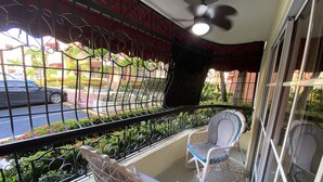 A balcony with a view of a street, a ceiling fan, and two chairs. - Spacious 3-bedroom Apartment in Santo Domingo! (Santo Domingo Norte)