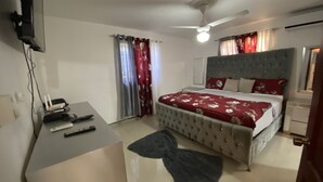 A bedroom with a bed, a desk, a ceiling fan, and a TV mounted on the wall. - Spacious 3-bedroom Apartment in Santo Domingo! (Santo Domingo Norte)
