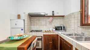 A compact kitchen with a refrigerator, microwave, stove, and sink. - Split Level Aprtment (Rome)