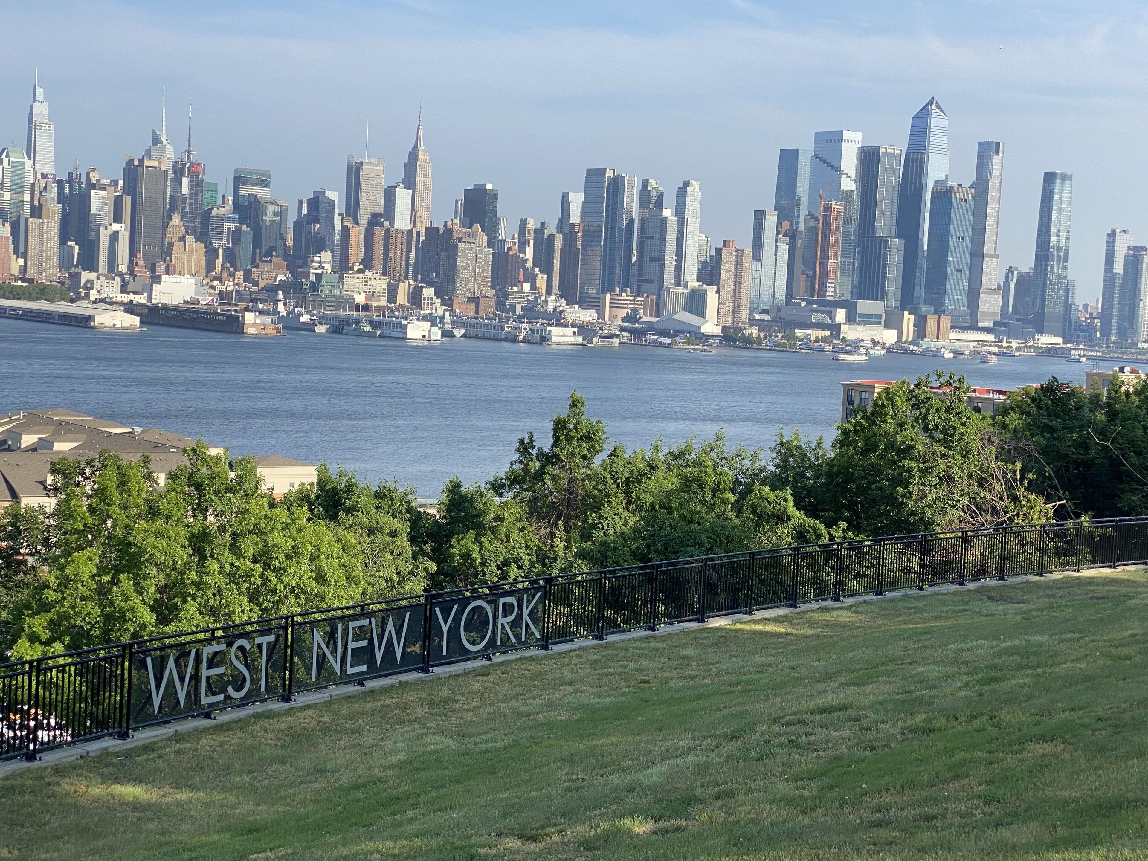 Vista del horizonte de la ciudad de Nueva York sobre el río Este, con el letrero de West New York en primer plano.