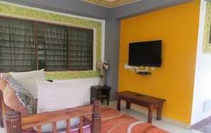 A room with a bed, a television mounted on the wall, a small table, and a window with curtains. - Villa Tuffah 3 Minutes Walk to the Beach - The Villa Comprises (Watamu)