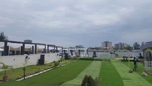 Une cour avec une pelouse, un élément décoratif aquatique et un bâtiment doté d’une façade en verre.