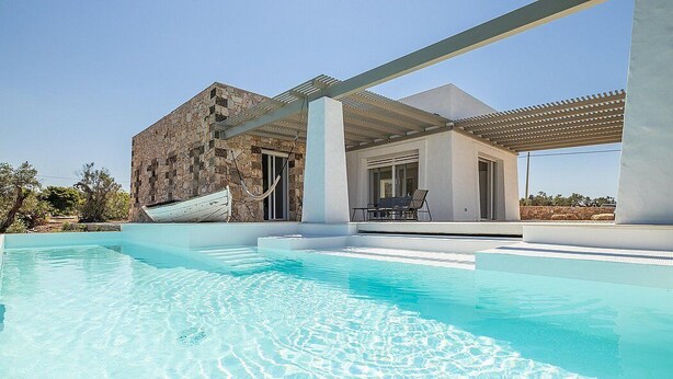 Ein moderner Poolbereich mit einem Steinhaus und einer überdachten Terrasse.