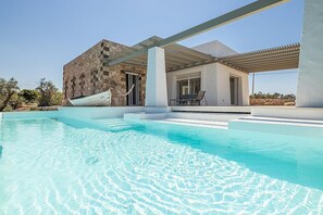 A modern pool area with a stone building and a covered patio.