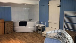 Un baño con una bañera, un lavabo blanco, una silla blanca y un mueble de madera.