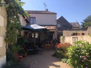 A courtyard with a covered seating area, surrounded by potted plants and flowers. - Charming house on Loire Deux Sevre Border (Argenton L'Eglise)