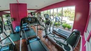 A gym with treadmills, elliptical machines, and exercise balls.
