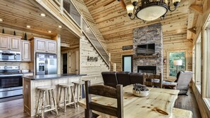 Un intérieur spacieux de chalet en bois, comprenant une cuisine, un coin repas et une cheminée.