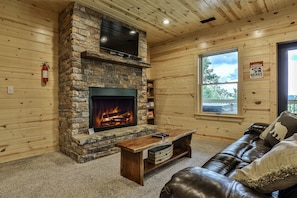 A cozy living room with a stone fireplace, a leather couch, and a wooden coffee table.