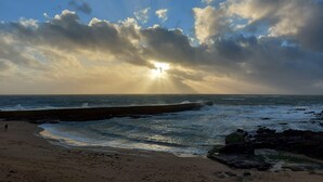 A beach with waves, a pier, and a person walking.