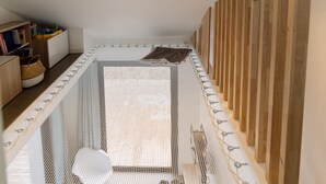 A room with a bunk bed, a small bookshelf, and a woven basket.