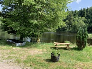 A lakeside picnic area with a wooden bench and a boat. - Small cottage in the heart of nature (Rupt-sur-Moselle)